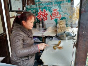 Woman making spun sugar lollipops in shapes like butterflies.